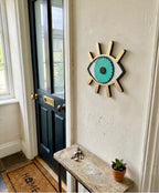 Decorative wall art of an eye on a white wall next to a black door.